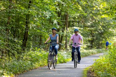 Ehepaar fährt auf dem Radweg durch den Wald