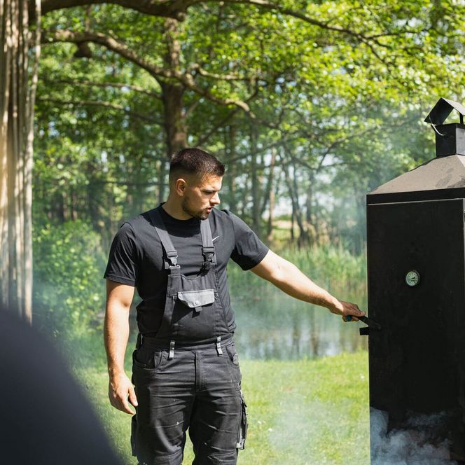Fischer vor Räucherofen im Sommer