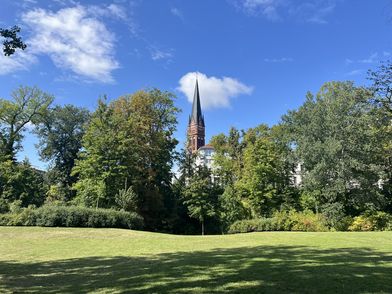 Blick vom Park aus auf den Kirchturm der Kath. Kirche Heiliges Kreuz
