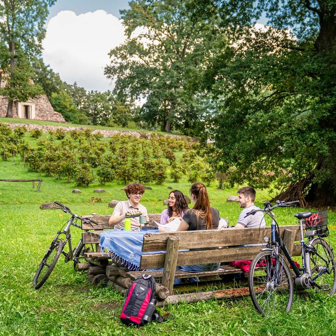 Radfahrer pausieren auf einer Bank an der Feldsteinpyramide Garzau