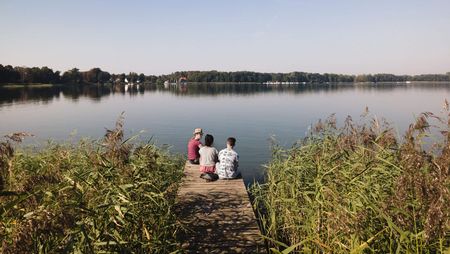 Drei Personen sitzen auf einem Steg am Großen Storkower See