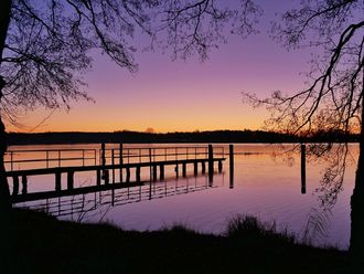 Kładka nad jeziorem Schwielochsee o zachodzie słońca zimą