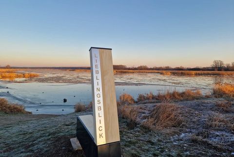 Eine Stele steht bei Sonnenaufgang vor dem Fluss Oder