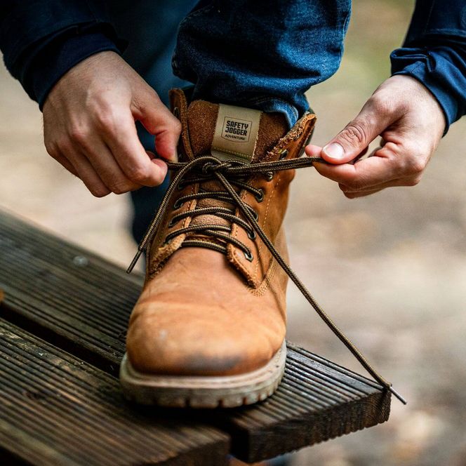 Detailaufnahme: Wanderer bindet die Schnürsenkel seiner Wanderschuhe