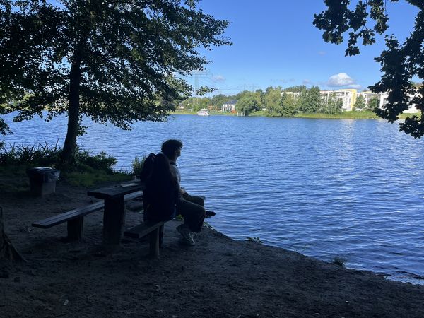 Person sitzt auf eine Bank am Kalksee mit Blick auf das andere Ufer