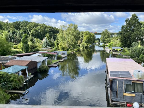 Ausblick von einer Holzbrücke auf ein Fließ mit Booten