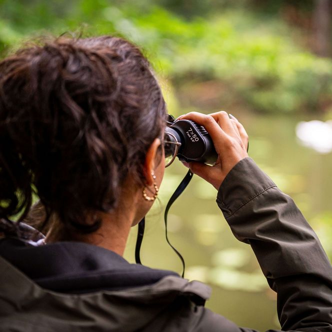 Frau schaut durch Fernglas im Herbst beim Wandern am Kupferhammer Schlaubetal