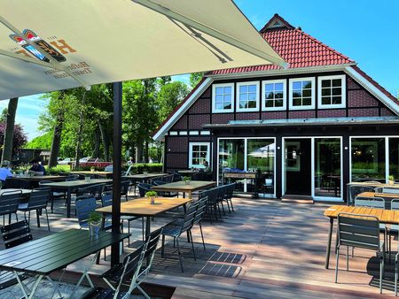 Blick auf Haus mit Terrasse und Sitzgarnituren davor