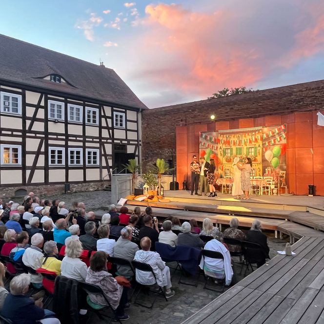 Opernaufführung in einer Burgkulisse vor einem Sonnenuntergang
