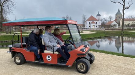 Vier Personen sitzen im Golfcar und schauen sich das Schlossgut an